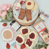 Afternoon cream tea hamper from above showing, scones, cream, jam, tea, flapjack, brownie and shortbread.